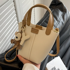 Modische zweifarbige Bucket Bag aus creme-braunem Leder mit Anhänger und Gurt