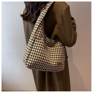 Detail of classic houndstooth tote bag with brown leather label on textured fabric