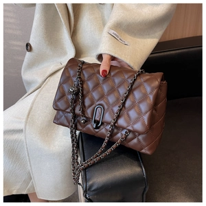 Close-up of coffee brown quilted leather texture with black metal chain and ring clasp