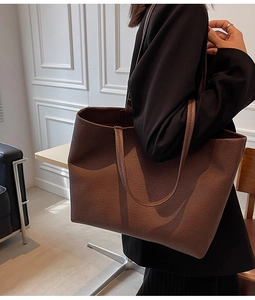 Detail of a large brown pebble-grain tote bag with comfortable double shoulder straps