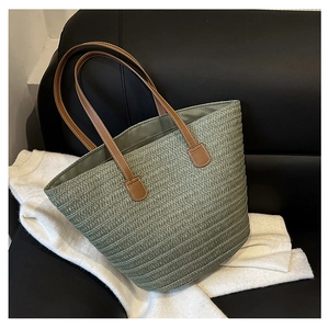 Detailed texture of green woven tote bag with brown leather handles and white stitching
