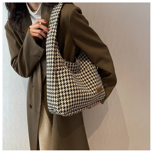 Close-up of houndstooth tote bag texture and leather label on shoulder strap