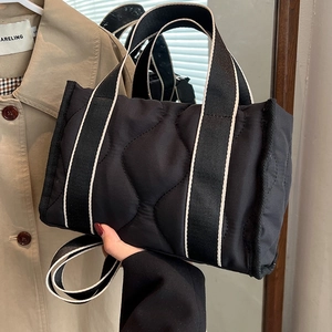 Bolso tote de nailon acolchado negro con asas a rayas y una correa de hombro ajustable