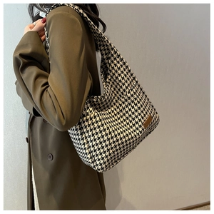 Detail of classic houndstooth knit tote bag with premium brown leather logo patch