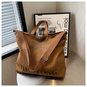 Detail of adjustable strap and textured dark brown canvas on large tote bag