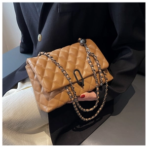 Close-up of brown quilted leather bag with black metal oval buckle and chain strap