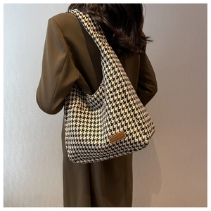 Detail shot of large houndstooth tote bag with brown leather logo patch on woven fabric
