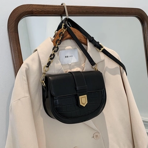 Fashionable black saddle crossbody bag with crocodile texture and gold shield buckle