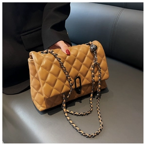 Detail of camel quilted crossbody bag featuring chain strap and matte black clasp closure
