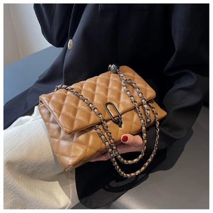 Close-up of brown quilted leather bag with black metal oval buckle and chain strap