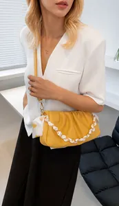 Détail du sac nuage jaune plissé avec bandoulière chaîne enroulée d'un foulard en soie