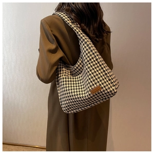 Detail of houndstooth tote bag showing thick knit texture and brown leather patch