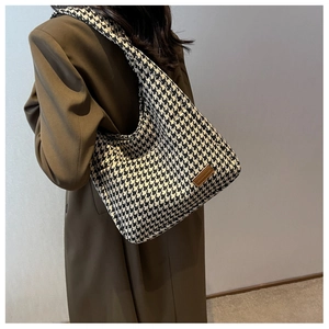 Close-up of the houndstooth fabric texture and leather logo detail on the tote bag