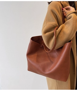 Close-up of caramel tote bag with lychee leather texture worn over a wool coat