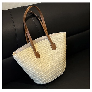 Close-up of beige woven straw tote bag texture and brown leather handles on dark sofa