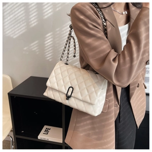 Chic beige quilted chain bag for women worn over the shoulder with a casual brown blazer
