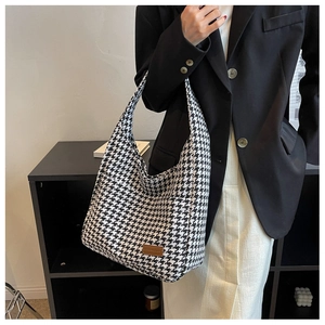 Detail of classic houndstooth tote bag featuring a brown leather fashion brand tag