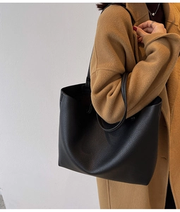 Close-up of black lychee-textured leather tote bag worn with a brown wool coat