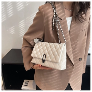 Detail of white quilted crossbody bag with U-shaped lock and leather chain strap