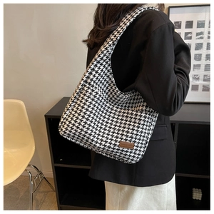 Detail of high-capacity houndstooth tote bag with brown leather logo patch for work