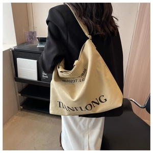 Detail of a large beige canvas tote bag with black lettering shown in a stylish home setting