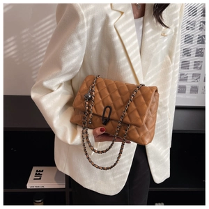 Close-up of brown quilted leather bag featuring a black chain strap and metal U-ring detail