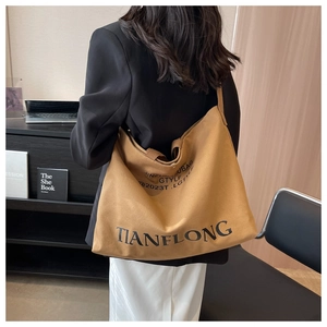 Large khaki canvas tote bag worn by a model in a modern urban lifestyle setting