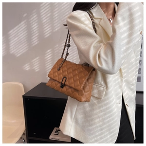 Close-up of brown quilted leather bag with dark metal chain strap and decorative lock