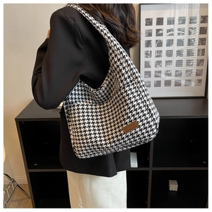 Detail of large houndstooth tote bag with brown leather logo patch on shoulder strap
