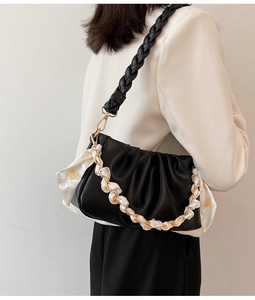 Detail van zwarte wolktas met gevlochten leren riem en hartvormige sjaalketting