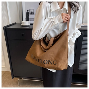 Close-up of large brown canvas tote bag texture with shoulder strap and text detail