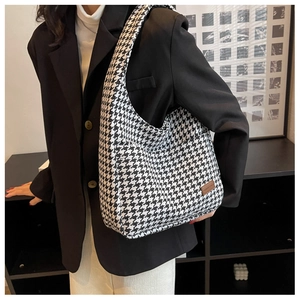 Detail of classic black and white houndstooth pattern tote with brown leather patch