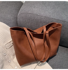 Detail of dark brown pebble texture tote bag on a gray sofa with high quality stitching