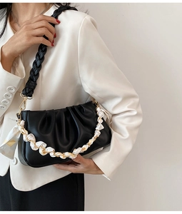 Detail van zwarte geplooide cloud bag met geweven riem en witte satijnen gouden ketting