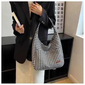 Detail of classic black and white houndstooth tote bag with brown leather logo patch
