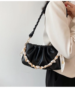 Detail van zwarte geplooide cloud bag met gouden ketting en zijden sjaal handvat