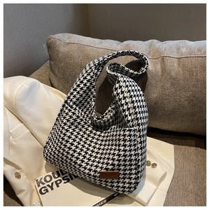 Close-up of houndstooth tote bag with leather detail on a soft fabric sofa background