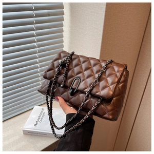 Detail of dark brown quilted crossbody bag featuring metal buckle and chain strap