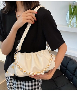 Detail van de crème cloud bag met geweven schouderband en zijden sjaalketting