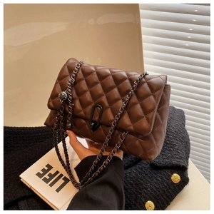 Detail of dark brown quilted leather bag with matte U-shaped clasp and chain strap