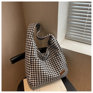 Macro detail of houndstooth woven fabric and brown leather logo tag on a large tote bag