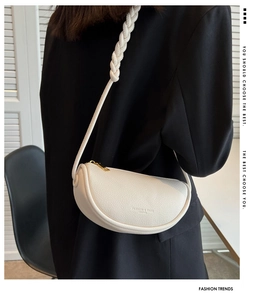 Detail of off-white lychee leather saddle bag with woven rope shoulder strap and gold zipper