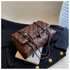 Detail of coffee brown quilted leather bag with black metal buckle and chain strap