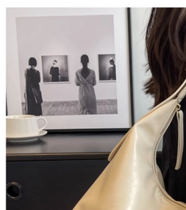 Detail view of a beige hobo bag with zipper and decorative long leather pull tab strap