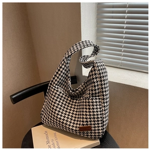Detailed texture of black and white houndstooth fabric on a stylish hobo tote bag