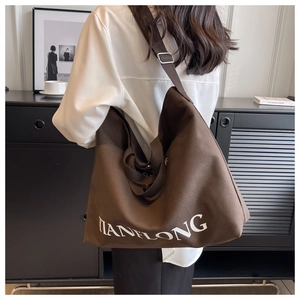 Brown large capacity canvas tote bag with adjustable strap worn by a model