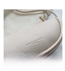 Close-up of litchi grain leather texture and embossed logo on beige saddle bag