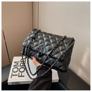 Close-up of black quilted leather shoulder bag with dark grey chain and metal ball charm