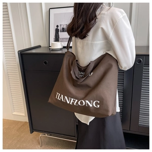 Coffee brown large canvas tote bag shown worn by a model in a minimalist interior setting