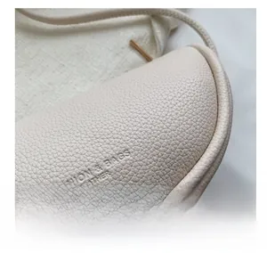 Close-up of creamy white faux leather saddle bag with pebble texture and metallic zipper